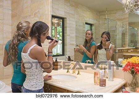Stock Photograph - Hispanic teenagers applying makeup in bathroom mirror. Fotosearch