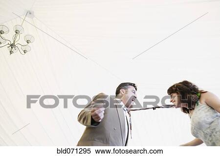 Stock Photography - Hispanic woman biting husband's tie. Fotosearch