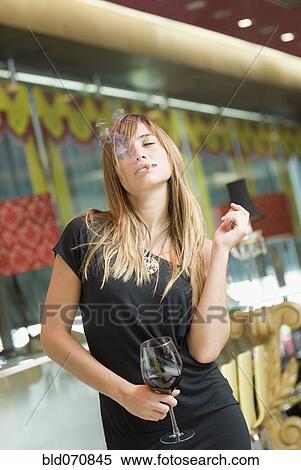 Stock Photography - Hispanic woman drinking wine and smoking. Fotosearch