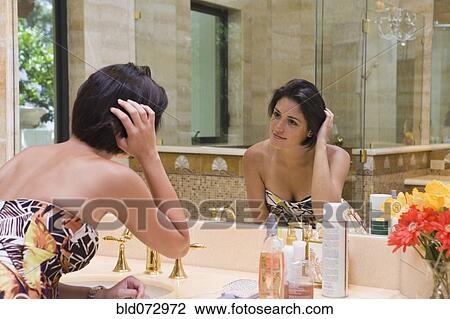 Hispanic woman fixing hair in bathroom mirror View Large Photo Image Stock Image - Hispanic woman fixing hair in bathroom mirror. Fotosearch