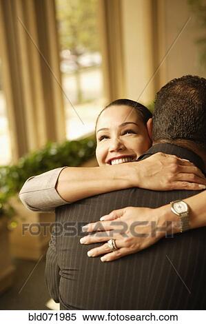 Stock Photography - Hispanic woman hugging husband. Fotosearch