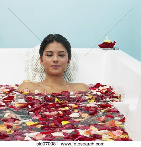 Stock Image - Hispanic woman in bathtub with flower petals. Fotosearch