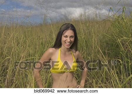 Stock Image - Hispanic woman laughing in tall grass. Fotosearch