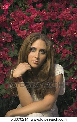 Picture - Hispanic woman sitting in front of flowers. Fotosearch