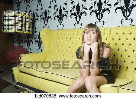Stock Photo - Hispanic woman sitting on retro sofa. Fotosearch