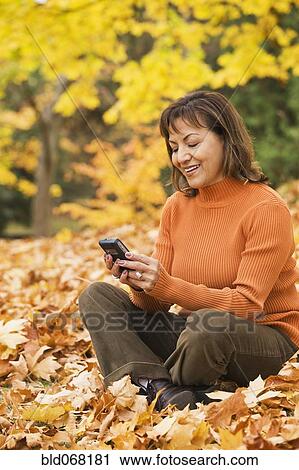 Hispanic woman using cell phone outdoors in autumn View Large Photo Image Stock Image - Hispanic woman using cell phone outdoors in autumn. Fotosearch
