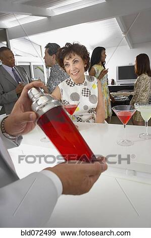 Stock Photo - Host mixing martini cocktails at party. Fotosearch