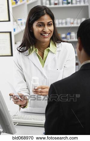 Stock Image - Indian female pharmacist talking to customer. Fotosearch
