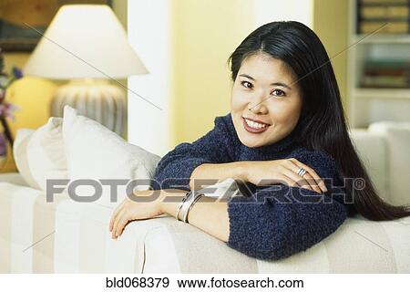 Korean woman sitting on sofa View Large Photo Image Stock Photo - Korean woman sitting on sofa. Fotosearch