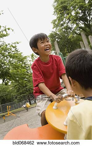 Stock Image - Laughing Asian boy playing on playground. Fotosearch