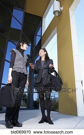 Stock Image - Low angle view of Asian businesswomen talking. Fotosearch