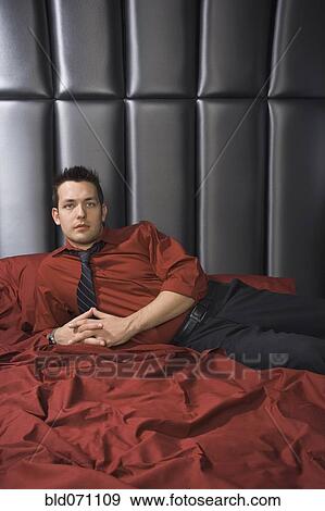 Stock Photo - Man wearing shirt and tie on bed. Fotosearch