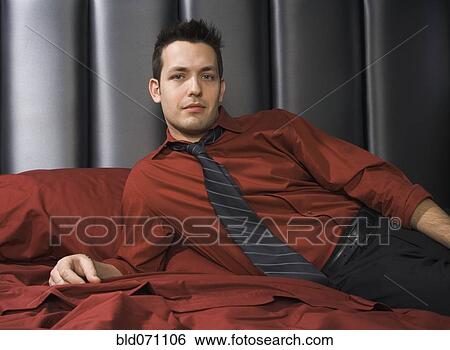 Stock Photograph - Man wearing shirt and tie on bed. Fotosearch