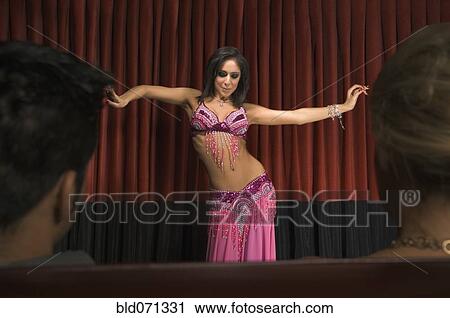 Stock Image - Middle Eastern woman belly dancing on stage. Fotosearch