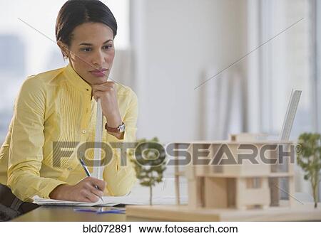 Stock Image - Mixed race architect studying building model. Fotosearch