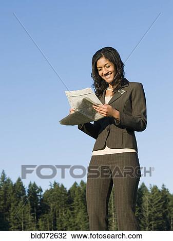 Mixed race businesswoman reading newspaper outdoors View Large Photo Image Stock Image - Mixed race businesswoman reading newspaper outdoors. Fotosearch