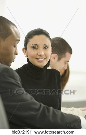 Stock Image - Mixed race businesswoman smiling in meeting. Fotosearch