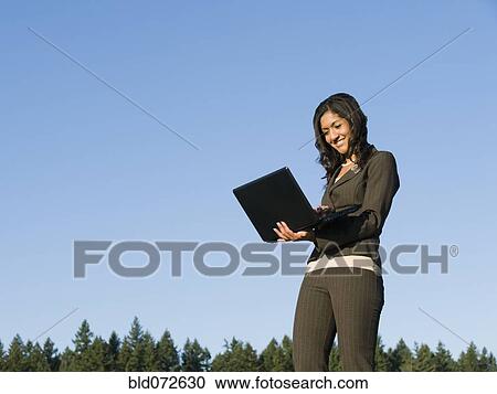 Mixed race businesswoman using laptop outdoors View Large Photo Image Stock Image - Mixed race businesswoman using laptop outdoors. Fotosearch