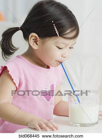 Stock Photography - Mixed race girl drinking milk with straw. Fotosearch