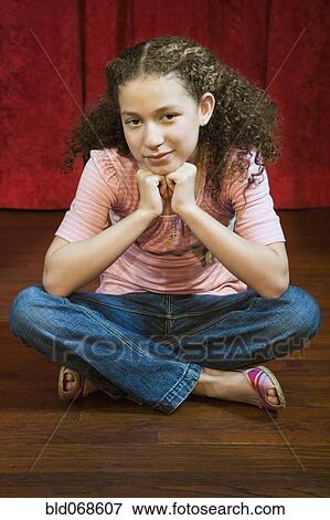 Stock Photo - Mixed race girl sitting cross-legged on stage. Fotosearch