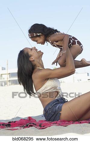 Stock Photography - Mixed race mother holding daughter at beach. Fotosearch