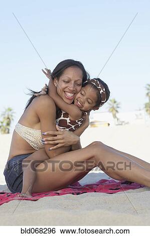 Mixed race mother hugging daughter at beach View Large Photo Image Stock Photograph - Mixed race mother hugging daughter at beach. Fotosearch