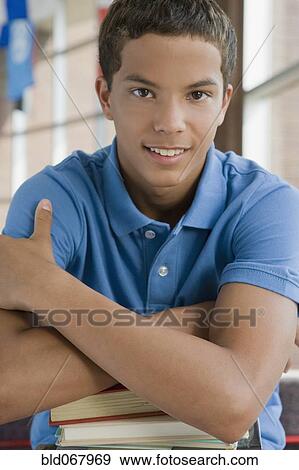 Stock Photo - Mixed race teenager leaning on stack of books. Fotosearch