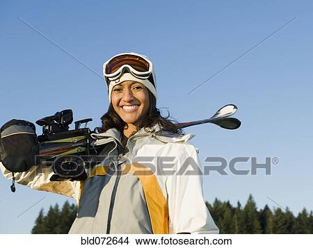 Picture - Mixed race woman holding skis. Fotosearch