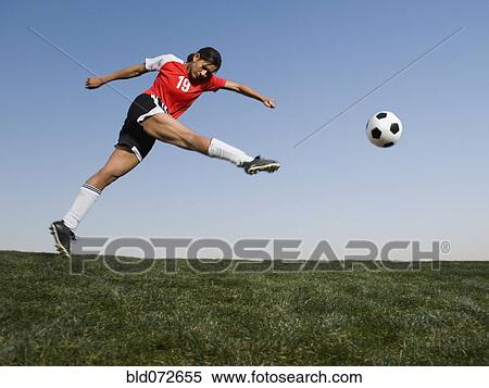 Stock Photography - Mixed race woman kicking soccer ball. Fotosearch