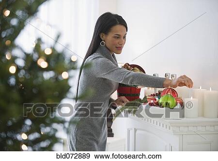 Stock Photo - Mixed race woman lighting candles on fireplace mantel. Fotosearch