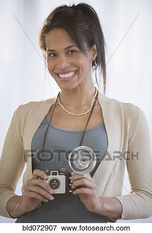 Stock Photo - Mixed race woman posing with antique camera. Fotosearch