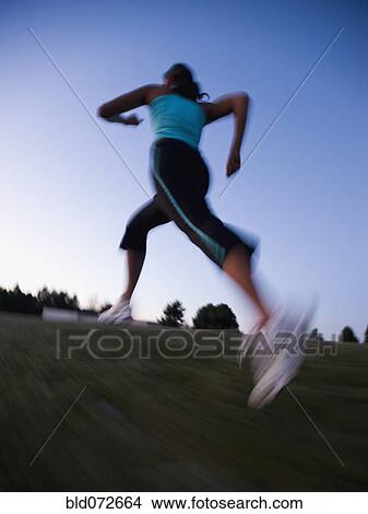 Picture - Mixed race woman running on grass. Fotosearch