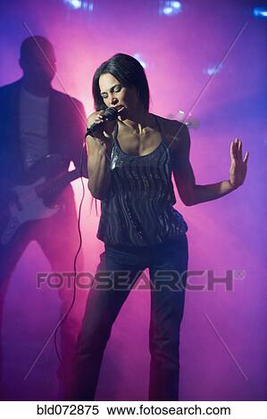 Stock Photography - Mixed race woman singing at nightclub. Fotosearch
