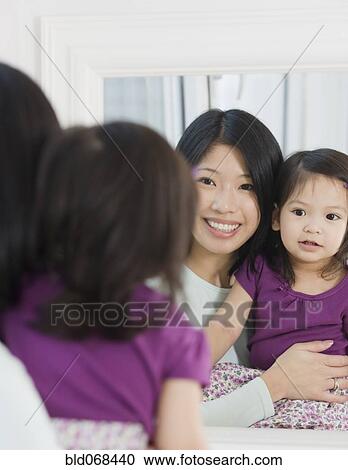Stock Image - Mother and daughter looking in mirror. Fotosearch