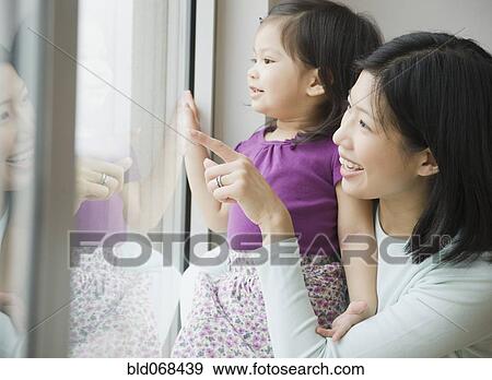 Stock Photo - Mother and daughter looking out window. Fotosearch