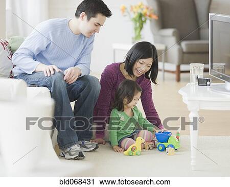 Mother and father playing with daughter in livingroom View Large Photo Image Stock Image - Mother and father playing with daughter in livingroom. Fotosearch