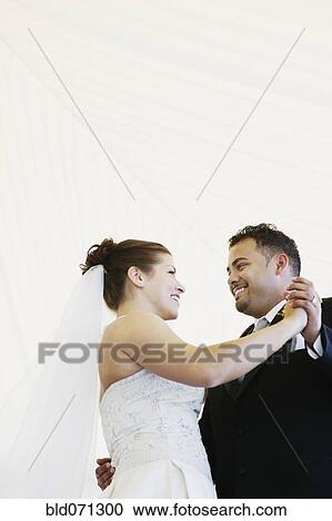 Stock Image - Multi-ethnic bride and groom dancing. Fotosearch