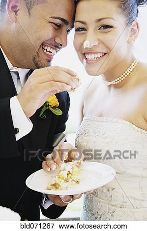Multi-ethnic bride and groom eating cake View Large Photo Image Stock Photo - Multi-ethnic bride and groom eating cake. Fotosearch