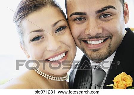 Stock Image - Multi-ethnic bride and groom hugging. Fotosearch