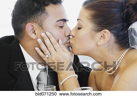 Stock Image - Multi-ethnic bride and groom kissing. Fotosearch