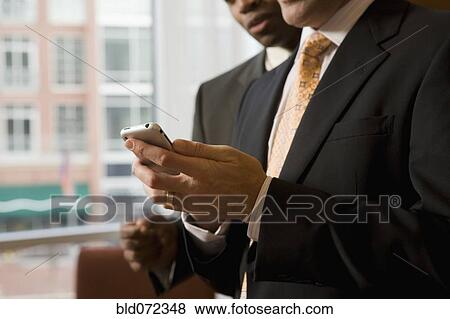 Stock Photo - Multi-ethnic business people looking at cell phone. Fotosearch
