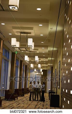 Stock Image - Multi-ethnic business people standing in corridor. Fotosearch