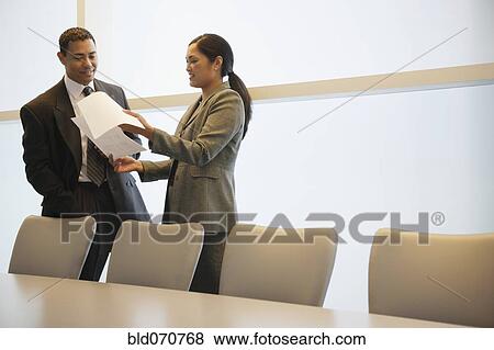 Stock Photo - Multi-ethnic businesspeople discussing paperwork. Fotosearch