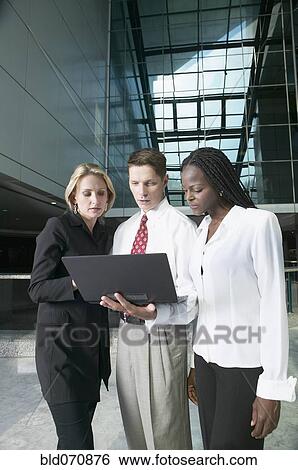 Stock Photograph - Multi-ethnic businesspeople looking at laptop. Fotosearch