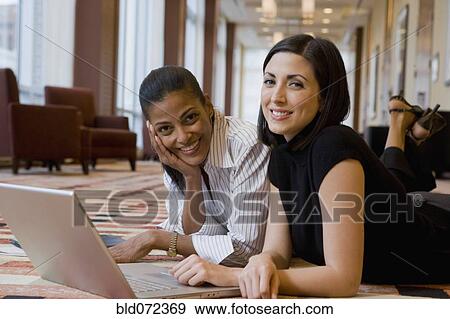 Multi-ethnic businesswoman laying on floor working on laptop View Large Photo Image Stock Photo - Multi-ethnic businesswoman laying on floor working on laptop. Fotosearch