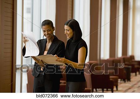 Multi-ethnic businesswoman reviewing paperwork in lobby View Large Photo Image Stock Photograph - Multi-ethnic businesswoman reviewing paperwork in lobby. Fotosearch