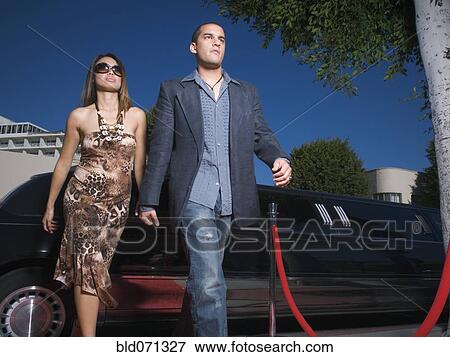 Stock Photo - Multi-ethnic couple walking away from limousine. Fotosearch