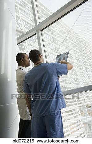 Stock Photography - Multi-ethnic doctor and nurse reviewing x-ray by window. Fotosearch