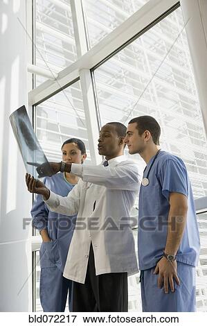 Stock Photo - Multi-ethnic doctor and nurses reviewing x-ray by window. Fotosearch