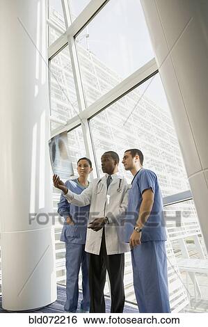 Stock Photograph - Multi-ethnic doctor and nurses reviewing x-ray by window. Fotosearch